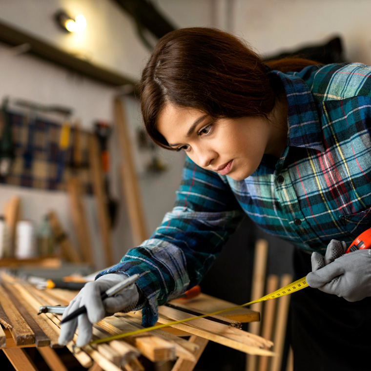 teen-working-workshop-measuring-wood-planks